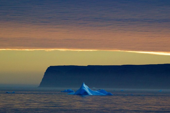 photo of iceberg in foreground, with Saunders Island in background