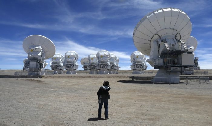 Telescopes on high desert plateau, photographer in foreground