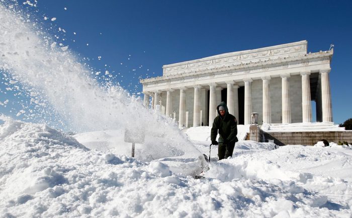 Worker using snowblower in front of federal building