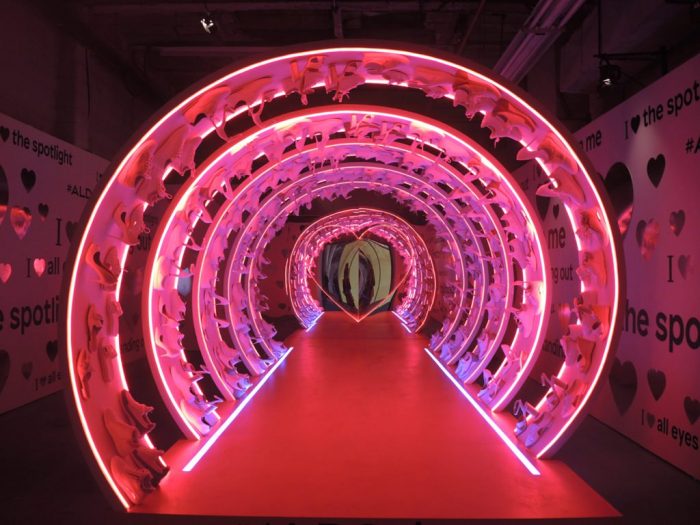 Modern art installation featuring neon tunnel of shoes