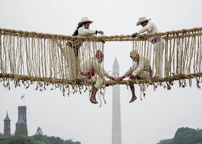 Men working on rope bridge, Washington Monument in background
