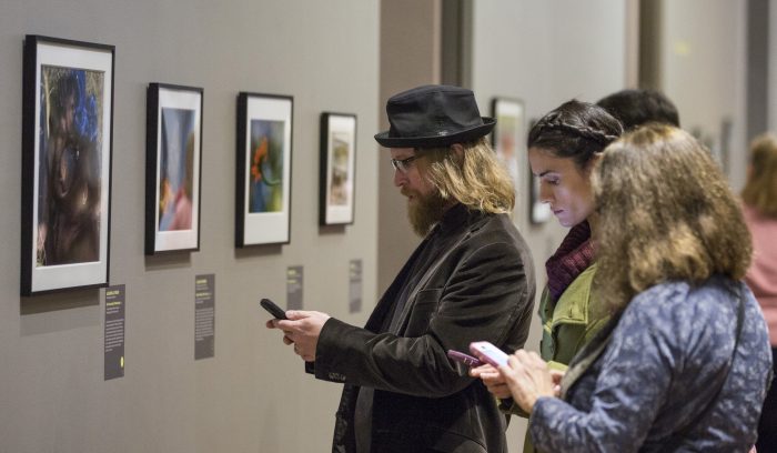 Gallery visitors check their phones