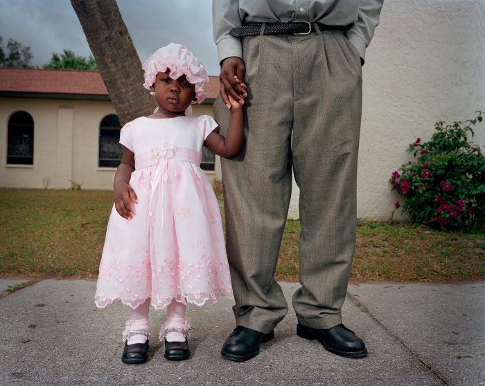 A young girl and her cousin wait after Creole Mass at a Catholic Church in Immokalee, Florida.