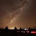 Silhouettes of people looking at starry night sky
