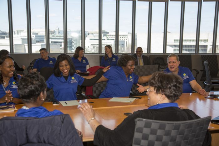 People seated around table with their arms on each others' shoulders