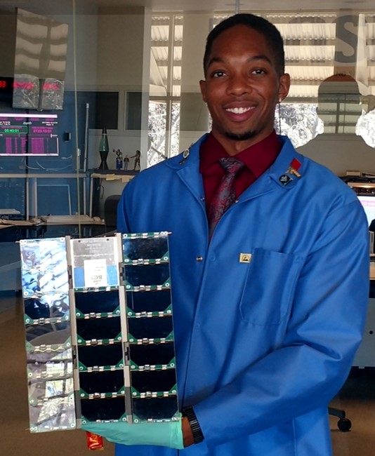 Moore in blue smock holding solar panels