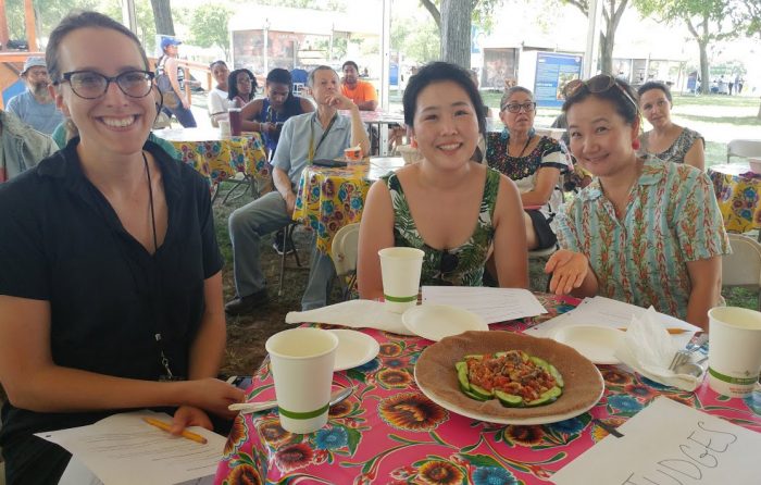 Three women smiling over winning plate of food