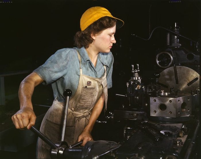 Woman in yellow cap and overalls operating machinery