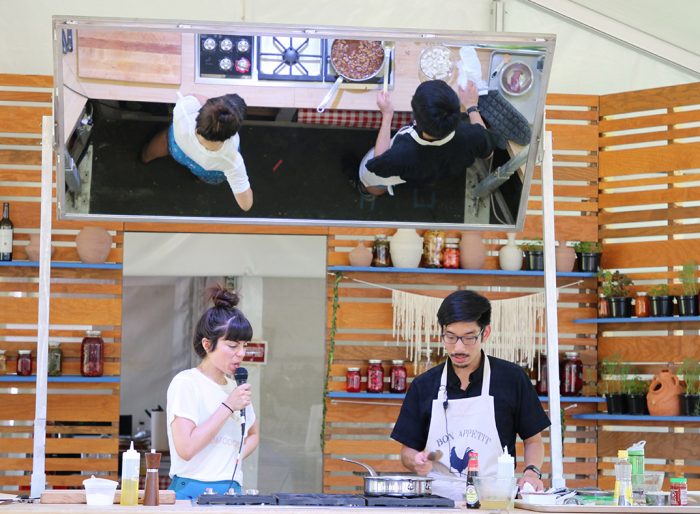 Cooking contestant and emcee reflected in overhead mirror