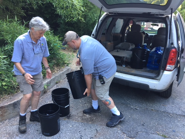 Man and woman loading buckets into back of SUV