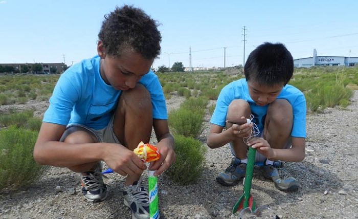 Two boys loading toy rockets with parachutes