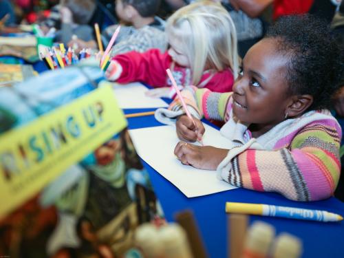 Child smiles brightly while drawing