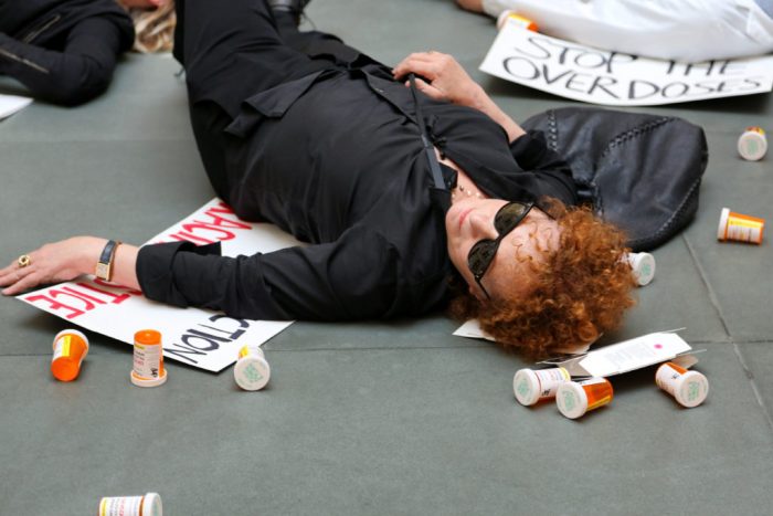 Woman lying on ground among empty pill bottles