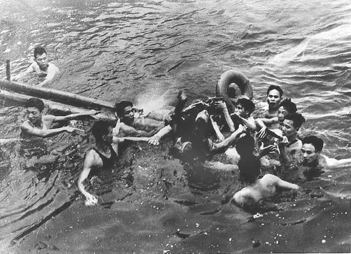 McCain in the water, surrounded by Vietnamese men