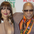 Rashida and Quincy Jones pose in front of scrim