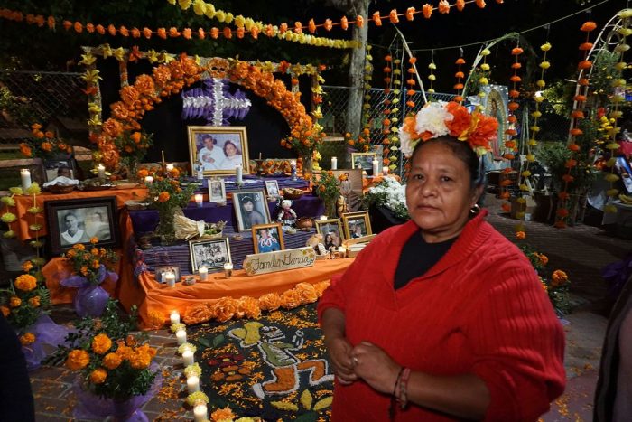 Woman stands before elaborate Day off the Dead altar