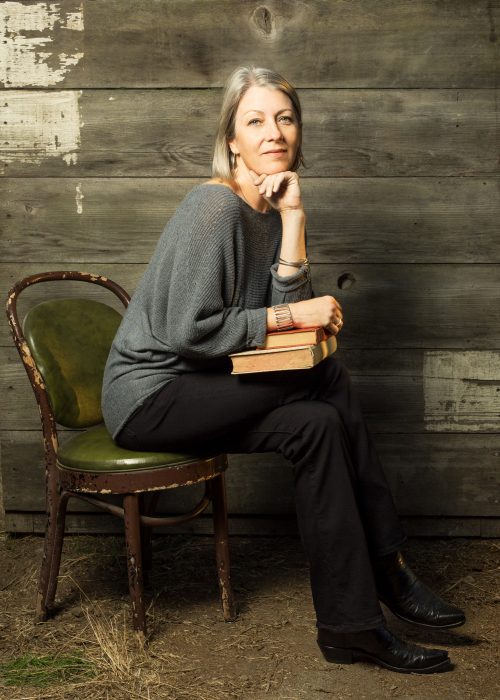 Hartig sitting on chair holding book sin her lap