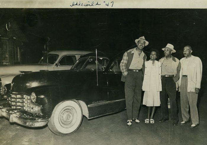 Family photo of family posed beside new car