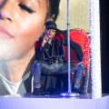 Monae poses on stage in front of a large photo of herself