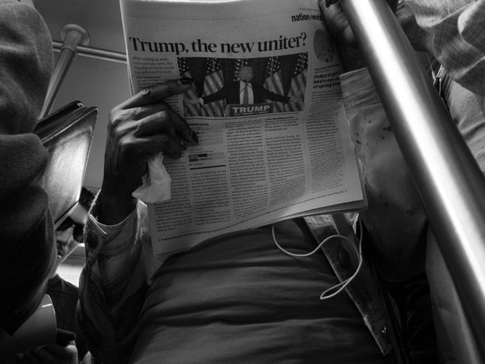 Commuter reading newspaper with Trump headline