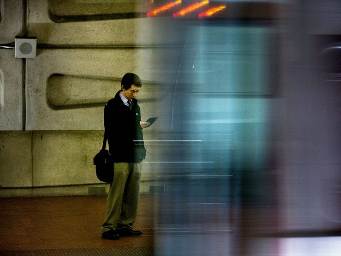 Commuter looking at phone as train goes by