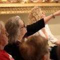 Volunteers in audience, one raising hand