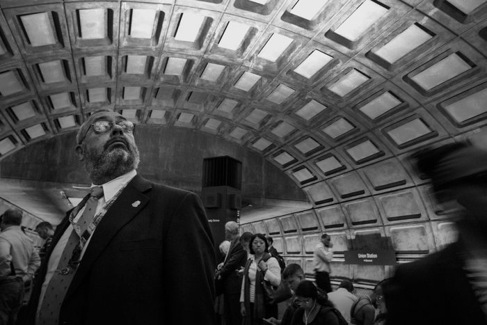 Commuters in Metro station, man in glasses looking upward