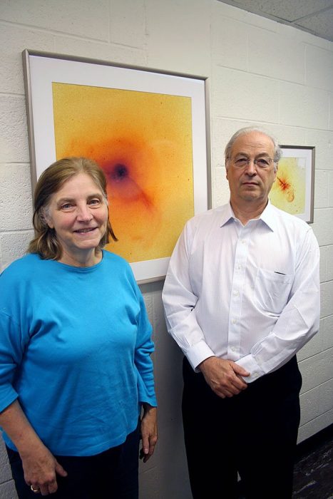 Couple stands in front of colorized image of galaxy