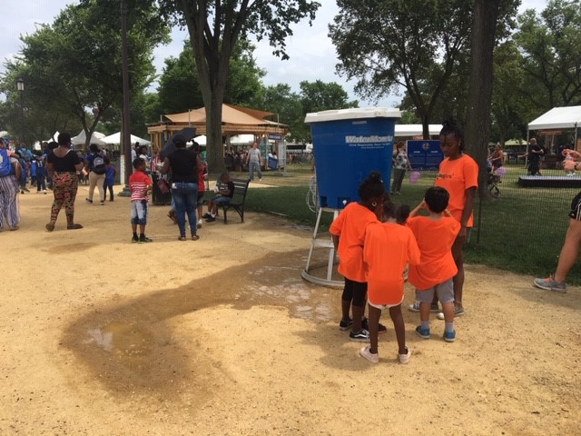Kids in orange shirts refill water bottles
