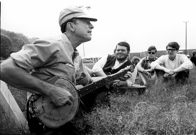 Seeger singing to people sitting in field