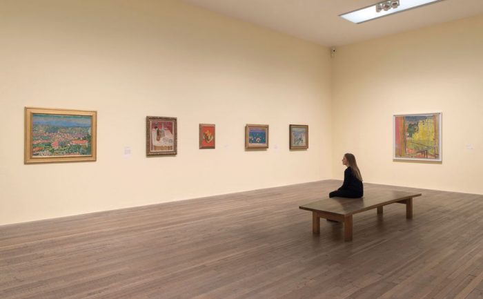 Woman sitting on bench in empty gallery