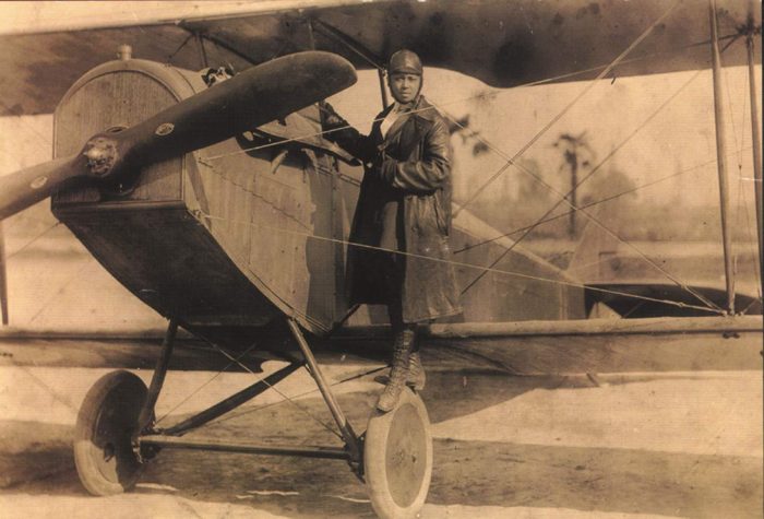 Coleman in flying gear poses with her airplane