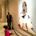 Child stands in front of portrait of Michelle Obama