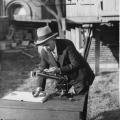 Man in suit and hat bending over a scientific instrument