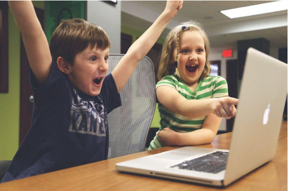 Children laughing and pointing at laptop