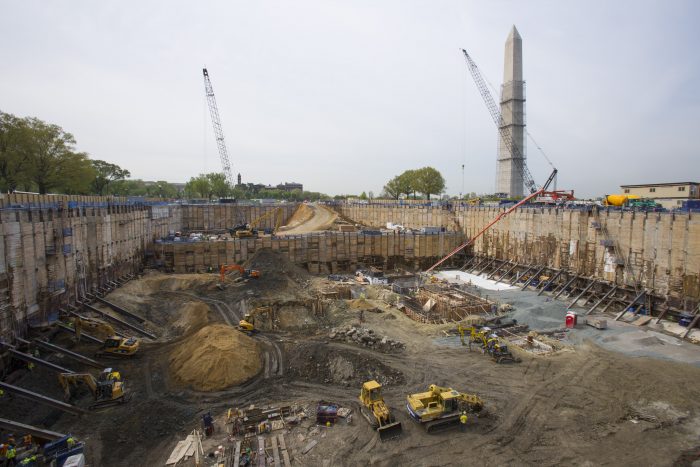 Construction site showing cranes and heavy equipment working on foundation.