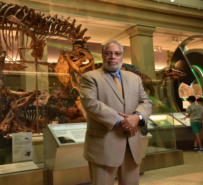Bunch, in tan suit, poses in Dinosaur Hall