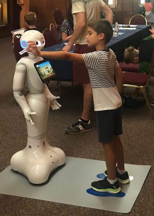 Boy holds card out to robot