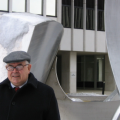 Goode, wearing beret, stands next to outdoor sculpture
