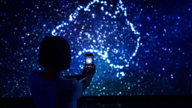 Still image of viewer with phone against starry background