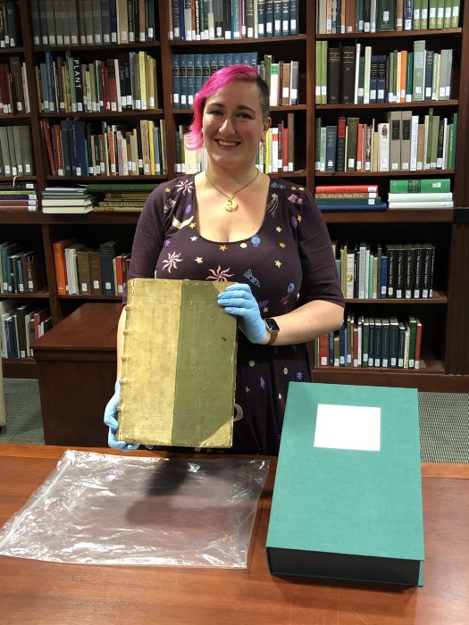 Alvis wearing gloves and holding rare book