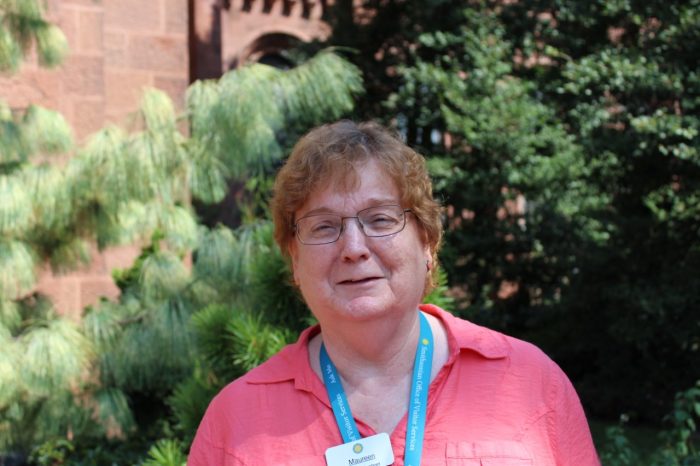 Woman in pink shirt with pine trees in background