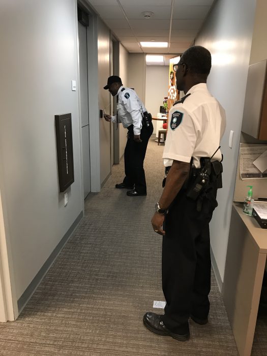 Two officers standing apart while one unlocks door