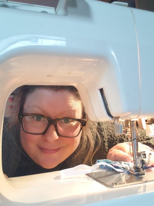 Laura McClure peeking beneath sewing machine