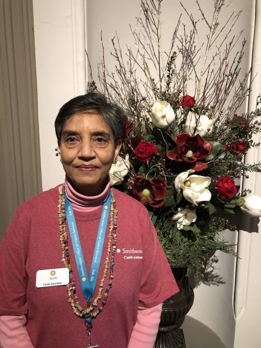 Alka Bhatnagar stands in front of a vase of roses