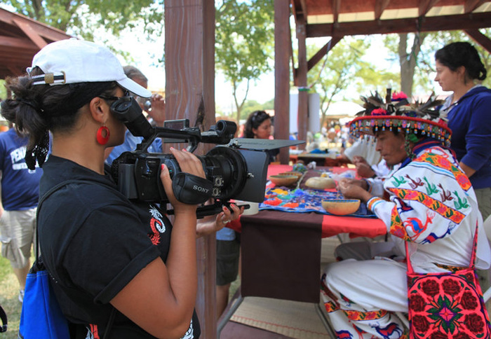 Young woman filming indigenous woman in traditional dress