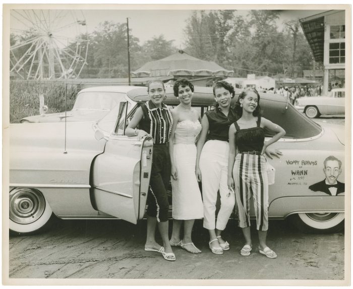 Four young women posing with convertible