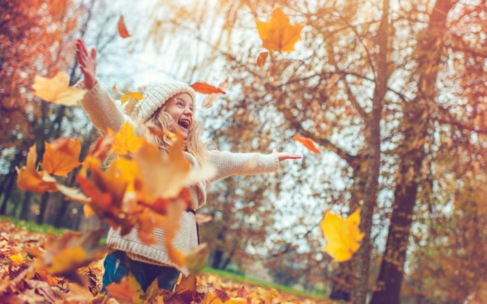 Young girl playing in fall leaves