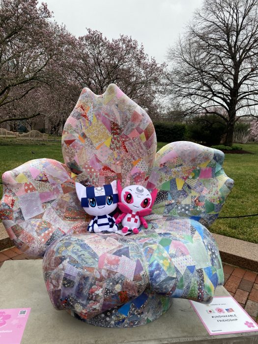 Two stuffed mascots sitting on cherry blossom sculpture