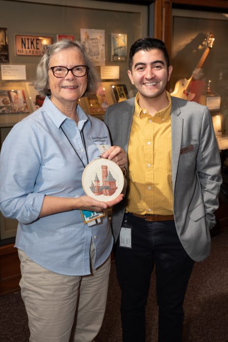 Chad with volunteer holding needlework image of Castle